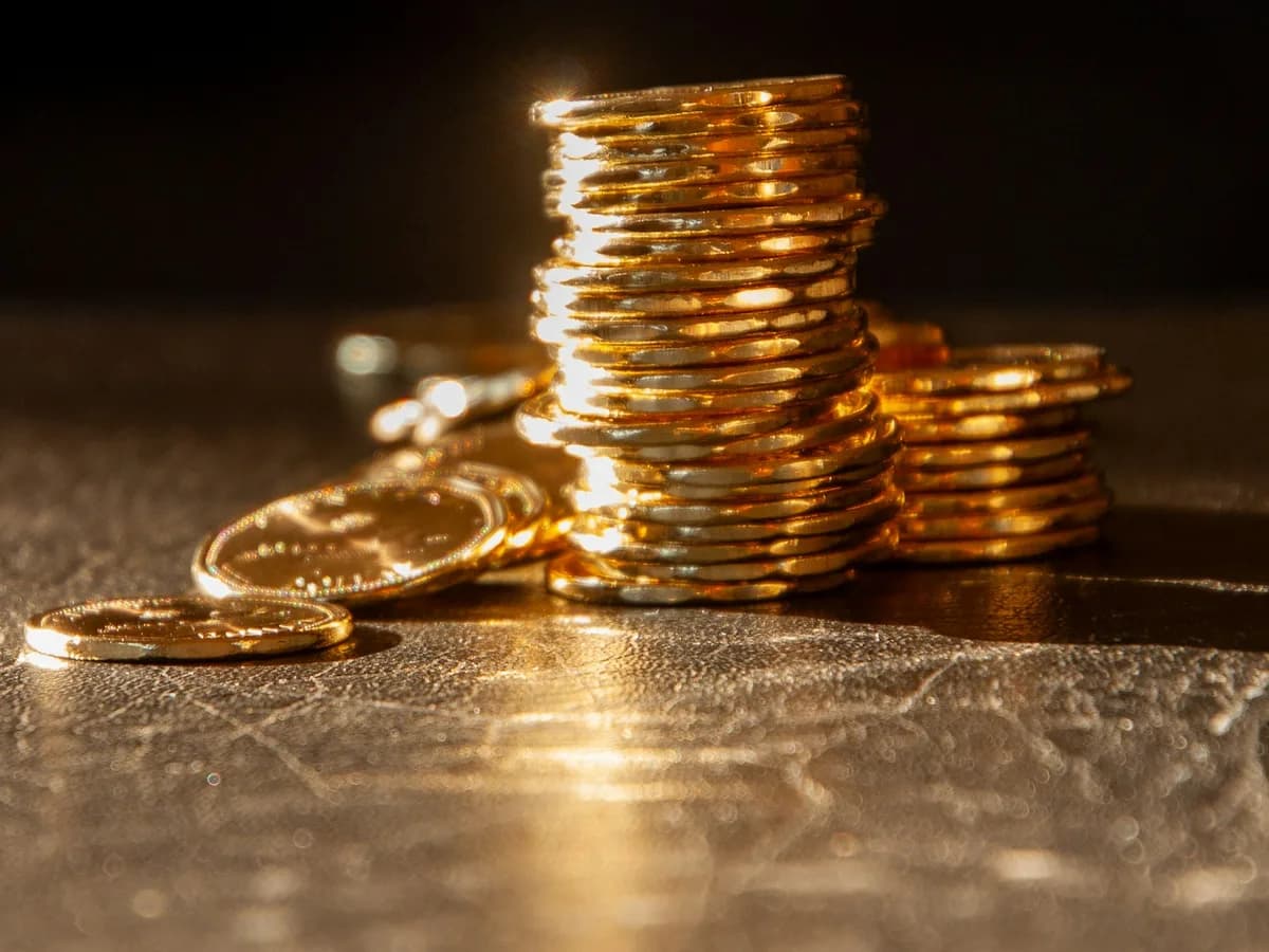 Montones de monedas doradas de altura creciente sobre una superficie oscura con luz cálida.