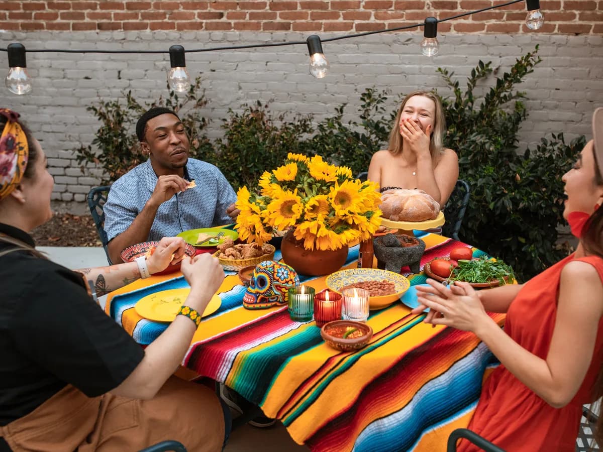 Un grupo de amigos riendo alrededor de una mesa en una cena al aire libre.