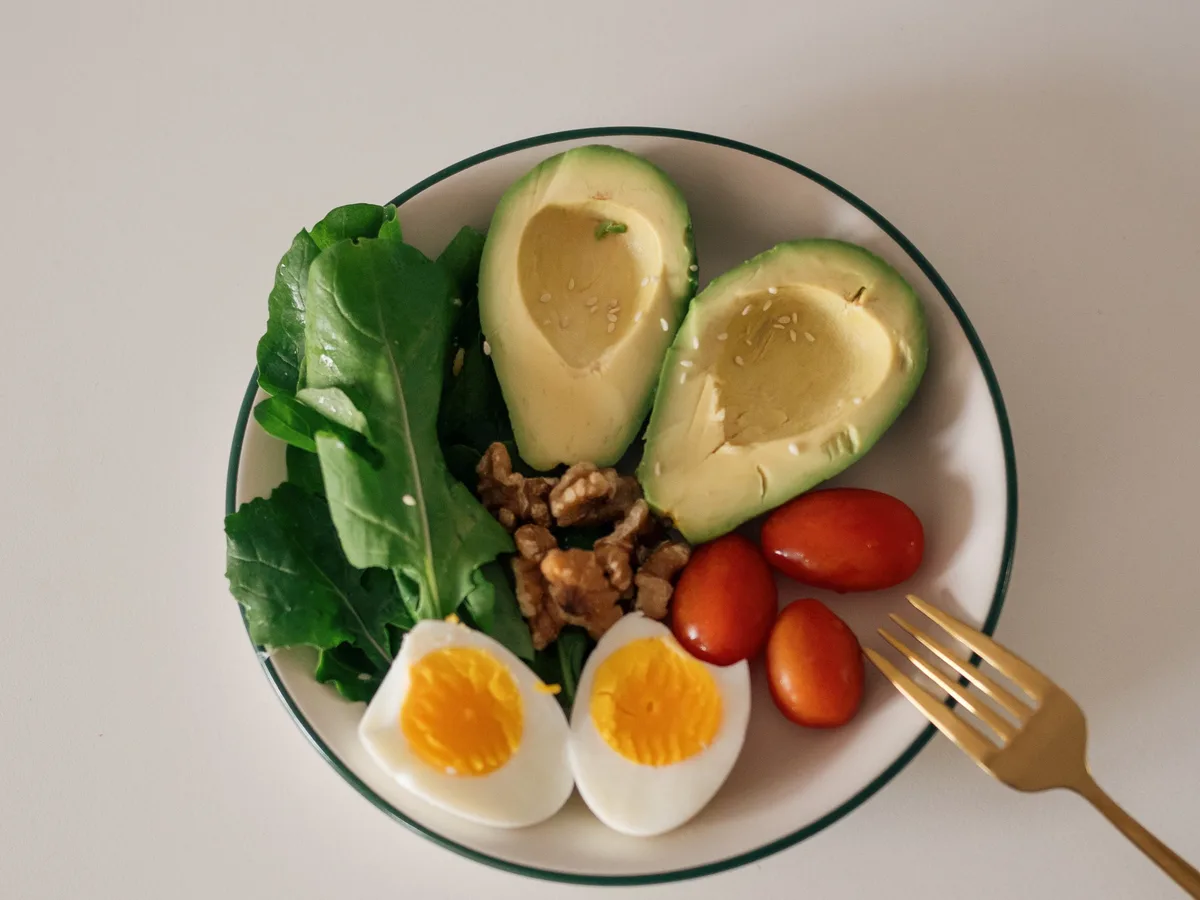 Overhead view of a breakfast bowl with fresh fruit and seeds, the kind of low-sugar meal that feeds the gut bacteria linked to calmer skin.