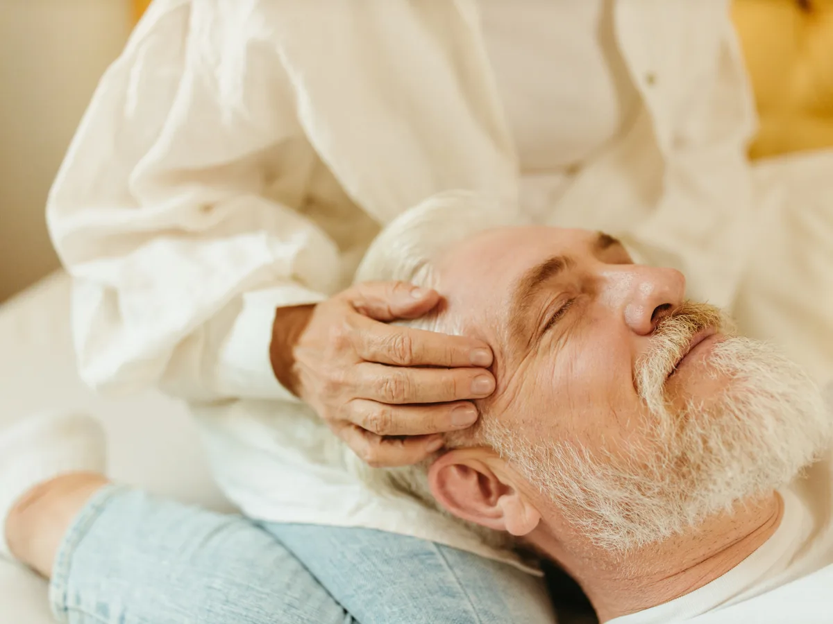 A man leaning back and receiving a firm scalp massage with both hands.